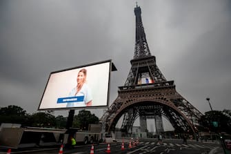 1212472638 A portrait of a nurse and of other representatives of professional groups who were mobilized during the COVID-19 pandemic are displayed during a tribute on a giant screen in front of The Eiffel Tower in Paris on May 10, 2020, on the eve of France's easing of lockdown measures in place for 55 days to curb the spread of the pandemic, caused by the novel coronavirus. (Photo by Thomas SAMSON / AFP) (Photo by THOMAS SAMSON/AFP via Getty Images)