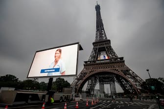 A portrait of a nurse and of other representatives of professional groups who were mobilized during the COVID-19 pandemic are displayed during a tribute on a giant screen in front of The Eiffel Tower in Paris on May 10, 2020, on the eve of France's easing of lockdown measures in place for 55 days to curb the spread of the pandemic, caused by the novel coronavirus. (Photo by Thomas SAMSON / AFP) (Photo by THOMAS SAMSON/AFP via Getty Images)