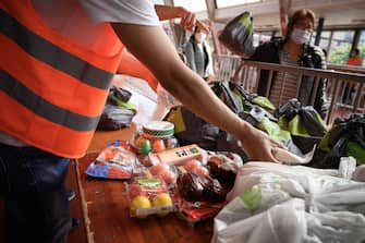 Volunteers hands out food bags at a free distribution point for the people in need on May 9, 2020, in Geneva, as the COVID-19 pandemic casts a spotlight on the usually invisible poor people of Geneva, one of the world's most expensive cities. (Photo by Fabrice COFFRINI / AFP) (Photo by FABRICE COFFRINI/AFP via Getty Images)