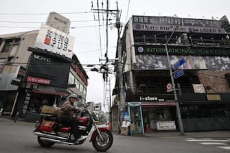 A man rides a motorcycle along a street in the popular nightlife district of Itaewon in Seoul on May 10, 2020. - South Korea's capital has ordered the closure of all clubs and bars after a burst of new cases sparked fears of a second coronavirus wave as President Moon Jae-in urged the public to remain vigilant. (Photo by Jung Yeon-je / AFP) (Photo by JUNG YEON-JE/AFP via Getty Images)