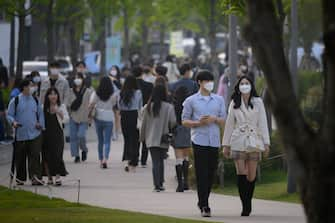 In a photo taken on May 10, 2020, people wearing face masks walk along a street in the Yeonnam district of Seoul. - South Korea announced its highest number of new coronavirus cases for more than a month on May 11, driven by an infection cluster in a Seoul nightlife district just as the country loosens restrictions. (Photo by Ed JONES / AFP) (Photo by ED JONES/AFP via Getty Images)