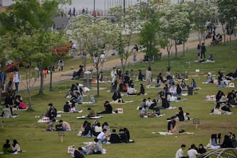 1212473224 TOPSHOT - In a photo taken on May 10, 2020, people sit in a park in Seoul. - South Korea announced its highest number of new coronavirus cases for more than a month on May 11, driven by an infection cluster in a Seoul nightlife district just as the country loosens restrictions. (Photo by Ed JONES / AFP) (Photo by ED JONES/AFP via Getty Images)