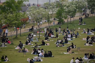 TOPSHOT - In a photo taken on May 10, 2020, people sit in a park in Seoul. - South Korea announced its highest number of new coronavirus cases for more than a month on May 11, driven by an infection cluster in a Seoul nightlife district just as the country loosens restrictions. (Photo by Ed JONES / AFP) (Photo by ED JONES/AFP via Getty Images)