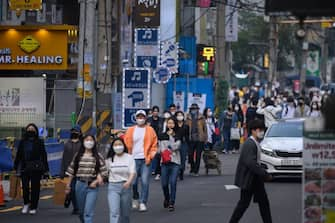 In a photo taken on May 10, 2020, people wearing face masks walk along a street in the Hongdae district of Seoul. - South Korea announced its highest number of new coronavirus cases for more than a month on May 11, driven by an infection cluster in a Seoul nightlife district just as the country loosens restrictions. (Photo by Ed JONES / AFP) (Photo by ED JONES/AFP via Getty Images)