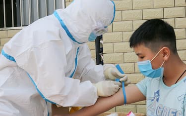 A medical staff member prepares to take a blood sample from a child to test for the COVID-19 novel coronavirus in Jian in China's central Jiangxi province on May 13, 2020. (Photo by STR / AFP) / China OUT (Photo by STR/AFP via Getty Images)