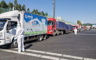A staff member (L) wearing protective gear speaks with a truck driver at an exit of a highway in Jilin in China's Jilin province on May 13, 2020. - A northeastern Chinese city has partially shut its borders and cut off transport links after the emergence of a local coronavirus cluster that has fuelled growing fears of a second wave of infections in China. (Photo by STR / AFP) / China OUT (Photo by STR/AFP via Getty Images)