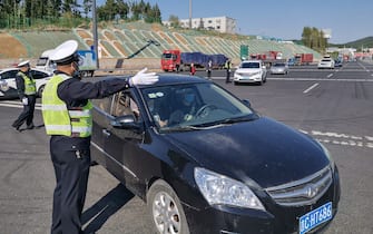 A police officer guides a car driver to register information at an exit of a highway in Jilin in China's Jilin province on May 13, 2020. - A northeastern Chinese city has partially shut its borders and cut off transport links after the emergence of a local coronavirus cluster that has fuelled growing fears of a second wave of infections in China. (Photo by STR / AFP) / China OUT (Photo by STR/AFP via Getty Images)