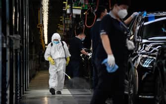 A cleaner wearing protective gear sprays disinfectant along a production line at a Mercedes Benz automotive plant during a media tour organised by the government in Beijing on May 13, 2020, as the country's industrial sector starts again following shutdowns during the COVID-19 coronavirus outbreak. (Photo by WANG Zhao / AFP) (Photo by WANG ZHAO/AFP via Getty Images)