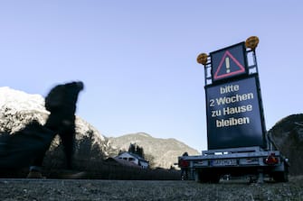 epa08418765 (FILE) - A man walks past a warning sign reading 'Please stay at home for two weeks', at the border between Germany and Austria, in Scharnitz, Germany, 16 March 2020 (reissued 13 May 2020). Media reports state on 13 May 2020 that Germany is planning to partially ease border controls as early as 16 May 2020, following a decision of the Cabinet. At the same time, Austria is planning to reopen the border with Germany as early as 15 June, media added.  EPA/PHILIPP GUELLAND *** Local Caption *** 55955865