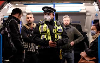 A police officer wearing PPE (personal protective equipment), including a face mask as a precautionary measure against COVID-19, stands with commuters as they travel in the morning rush hour on TfL (Transport for London) London underground Victoria Line trains from Finsbury Park towards central London on May 13, 2020, as people start to return to work after COVID-19 lockdown restrictions were eased. - Britain's economy shrank two percent in the first three months of the year, rocked by the fallout from the coronavirus pandemic, official data showed Wednesday, with analysts predicting even worse to come. Prime Minister Boris Johnson began this week to relax some of lockdown measures in order to help the economy, despite the rising death toll, but he has also stressed that great caution is needed. (Photo by Isabel INFANTES / AFP) (Photo by ISABEL INFANTES/AFP via Getty Images)