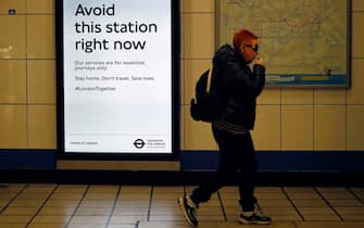 A commuter wearing passes a sign telling passes a sign advising passengers to "Avoid this Station right now" at Walthamstow undergound station in London on May 13, 2020, as people start to return to work after COVID-19 lockdown restrictions were eased. - Britain's economy shrank two percent in the first three months of the year, rocked by the fallout from the coronavirus pandemic, official data showed Wednesday, with analysts predicting even worse to come. Prime Minister Boris Johnson began this week to relax some of lockdown measures in order to help the economy, despite the rising death toll, but he has also stressed that great caution is needed. (Photo by Tolga Akmen / AFP) (Photo by TOLGA AKMEN/AFP via Getty Images)