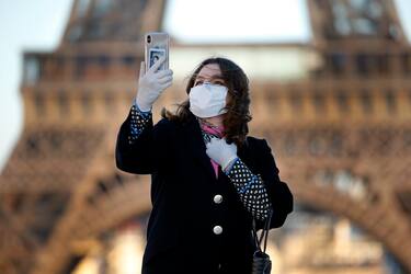 PARIS, FRANCE - MARCH 30: A woman wearing a mask and protective gloves takes a selfie in front of the Eiffel Tower during the Coronavirus epidemic (CODIV 19) on March 30, 2020 in Paris, France. The country is issuing fines for people caught violating its nationwide lockdown measures intended to stop the spread of COVID-19. The pandemic has spread to at least 182 countries, claiming over 30,000 lives and infecting hundreds of thousands more. (Photo by Chesnot/Getty Images)