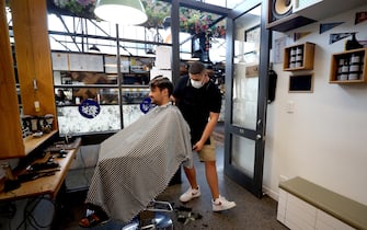 AUCKLAND, NEW ZEALAND - MAY 14:  A Barber wearing a face mask works on a customer's hair at Board & Blade Barbour Shop on May 14, 2020 in Auckland, New Zealand. New Zealand moves to COVID-19 Alert Level 2 in three stages starting from today with restaurants, cinemas, retail, playgrounds and gyms able to reopen with physical distancing and strict hygiene measures in place. Public gatherings are permitted for up to 10 people and New Zealanders are now able to travel domestically. Schools and early childhood centres will open from Monday 18 May while bars will be allowed to reopen from Thursday 21 May. New Zealand was placed under full lockdown on March 26 in response to the coronavirus (COVID-19) pandemic. (Photo by Hannah Peters/Getty Images)