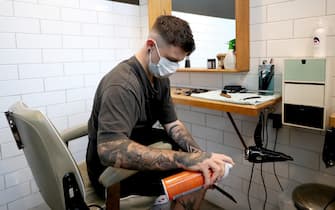 AUCKLAND, NEW ZEALAND - MAY 14:  A Barber wearing a face mask cleans his tools in between clients at Board & Blade Barbour Shop on May 14, 2020 in Auckland, New Zealand. New Zealand moves to COVID-19 Alert Level 2 in three stages starting from today with restaurants, cinemas, retail, playgrounds and gyms able to reopen with physical distancing and strict hygiene measures in place. Public gatherings are permitted for up to 10 people and New Zealanders are now able to travel domestically. Schools and early childhood centres will open from Monday 18 May while bars will be allowed to reopen from Thursday 21 May. New Zealand was placed under full lockdown on March 26 in response to the coronavirus (COVID-19) pandemic. (Photo by Hannah Peters/Getty Images)