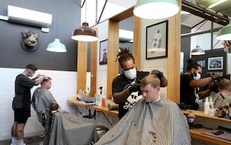 1224701922 AUCKLAND, NEW ZEALAND - MAY 14: A Barber wearing a face mask works on a customer's hair at Board & Blade Barbour Shop on May 14, 2020 in Auckland, New Zealand. New Zealand moves to COVID-19 Alert Level 2 in three stages starting from today with restaurants, cinemas, retail, playgrounds and gyms able to reopen with physical distancing and strict hygiene measures in place. Public gatherings are permitted for up to 10 people and New Zealanders are now able to travel domestically. Schools and early childhood centres will open from Monday 18 May while bars will be allowed to reopen from Thursday 21 May. New Zealand was placed under full lockdown on March 26 in response to the coronavirus (COVID-19) pandemic. (Photo by Hannah Peters/Getty Images)