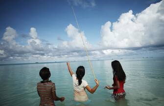 FUNAFUTI, TUVALU - NOVEMBER 28: Kids fish in the lagoon on November 28, 2019 in Funafuti, Tuvalu. TheÂ low-lyingÂ South Pacific island nationÂ of about 11,000 people has been classified as â  extremely vulnerableâ   to climate change by theÂ United Nations Development Programme.Â The worldâ  s fourth-smallest country is struggling to cope with climate change related impacts including five millimeter per year sea level rise (above the global average), tidal and wave driven flooding, storm surges, rising temperatures, saltwater intrusion and coastal erosion on its nine coral atolls and islands, the highest of which rises about 15 feet above sea level. In addition, the severity of cyclones and droughts in the Pacific Island region are forecast to increase due to global warming. Some scientists have predicted that Tuvalu could become inundated and uninhabitable in 50 to 100 years or less if sea level rise continues.Â The country is working toward a goal of 100 percent renewable power generation by 2025 in an effort to curb pollution and set an example for larger nations. Tuvalu is also exploring a plan to build an artificial island.   (Photo by Mario Tama/Getty Images)