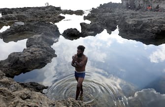 1193337383 TANNA, VANUATU - DECEMBER 04: A man stands in tide pool on the coast of the Pacific Ocean on December 04, 2019 in Tanna, Vanuatu. The island was hit hard by Cyclone Pam in 2015, a category 5 storm. Scientists have forecast that the strength of South Pacific cyclones will increase because of global warming. (Photo by Mario Tama/Getty Images)