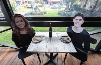 1224749653 SYDNEY, AUSTRALIA - MAY 14: Cardboard cutouts of human beings sitting at tables inside the Five Dock Dining restaurant on May 14, 2020 in Sydney, Australia. Restaurants and cafes in New South Wales are preparing to reopen with social distancing measures in place as the state government relaxes COVID-19 restrictions. From Friday 15 May cafes, restaurants and hotel dining areas are allowed to reopen but can only seat 10 patrons at a time and for at least four square metres of space per person. To make patrons feel more comfortable and like they are having a regular dining experience, Five Dock Dining owner Frank Angeletta will use cardboard customers to fill the empty space in his restaurant along with having taped background noise simulating guest "chatter" playing for ambience. (Photo by James D. Morgan/Getty Images)