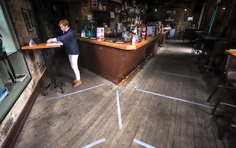 SYDNEY, AUSTRALIA - MAY 15: Lines displaying social distancing areas can be seen on the floor near Kazuko Nelson, the Licensee of the Hero of Waterloo pub in The Rocks, as she prepares a table for customers on May 15, 2020 in Sydney, Australia. Restrictions put in place in response to the COVID-19 outbreak have been eased in New South Wales as of today, with social distancing measures relaxed in response to Australia's declining number of confirmed coronavirus cases. From Friday 15 May cafes and restaurants along with pub and club dining areas are allowed to reopen for up to 10 patrons at a time. Outdoor gatherings of up to 10 people are now also permitted, while outdoor gyms, playgrounds, swimming pools can also open. Up to 10 guests can attend a wedding while 20 mourners are permitted for an indoor funeral, or 30 can attend if the service is outdoors. Religious gatherings and places of worship can have 10 worshipers at one time, while people are permitted to have up to five visitors in their homes at any one time. (Photo by David Gray/Getty Images)
