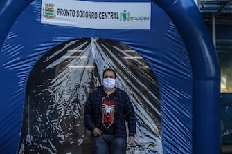 SAO GONCALO, BRAZIL - MAY 13: A man wearing a face mask walks through a disinfection tunnel at Dr. Armando Gomes de SÃ¡ Couto ER during the coronavirus (COVID-19) pandemic on May 13, 2020 in SÃ£o GonÃ§alo, Brazil. A disinfection tunnel is installed at entrance of the ERÂ in Ze Garoto neighborhood. According to the Brazilian Health Ministry, Brazil has 177,589 positive cases of coronavirus (COVID-19) and a total of 12.400 deaths. (Photo by Luis Alvarenga/Getty Images)