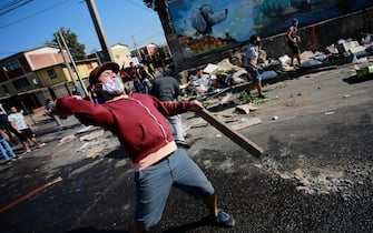 TOPSHOT - Demonstrators clash with riot police during a protest against Chilean President Sebastian Pinera's government amid the COVID-19 pandemic, in Santiago, on May 18, 2020. - Villagers in the populous commune of El Bosque, in southern Santiago, clashed with the police after protesting the lack of food and work as a result of the crisis caused by the coronavirus, which keeps the Chilean capital in total quarantine. (Photo by Pablo Rojas / AFP) (Photo by PABLO ROJAS/AFP via Getty Images)