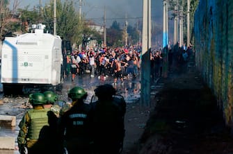 Demonstrators clash with riot police during a protest against Chilean President Sebastian Pinera's government amid the COVID-19 pandemic, in Santiago, on May 18, 2020. - Villagers in the populous commune of El Bosque, in southern Santiago, clashed with the police after protesting the lack of food and work as a result of the crisis caused by the coronavirus, which keeps the Chilean capital in total quarantine. (Photo by Pablo Rojas / AFP) (Photo by PABLO ROJAS/AFP via Getty Images)