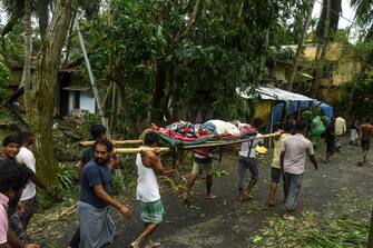 Residents carry Tapas Pramanik (C), 41, after his leg got broken by a tree fall the night before, in search of an ambulance or vehicle to take him to the hospital, following the landfall of cyclone Amphan in Khejuri area of Midnapore, West Bengal, on May 21, 2020. - At least 22 people died as the fiercest cyclone to hit parts of Bangladesh and eastern India this century sent trees flying and flattened houses, with millions crammed into shelters despite the risk of coronavirus. (Photo by Dibyangshu SARKAR / AFP) (Photo by DIBYANGSHU SARKAR/AFP via Getty Images)