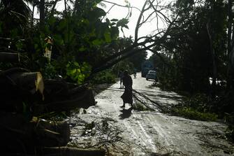 A woman removes debris from a road after the landfall of cyclone Amphan in Midnapore, West Bengal, on May 21, 2020. - The strongest cyclone in decades slammed into Bangladesh and eastern India on May 20, sending water surging inland and leaving a trail of destruction as the death toll rose to at least nine. (Photo by Dibyangshu SARKAR / AFP) (Photo by DIBYANGSHU SARKAR/AFP via Getty Images)