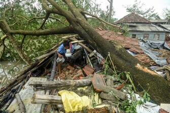 A man salvages items from his house damaged by cyclone Amphan in Midnapore, West Bengal, on May 21, 2020. - At least 22 people died as the fiercest cyclone to hit parts of Bangladesh and eastern India this century sent trees flying and flattened houses, with millions crammed into shelters despite the risk of coronavirus. (Photo by Dibyangshu SARKAR / AFP) (Photo by DIBYANGSHU SARKAR/AFP via Getty Images)