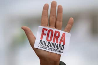 epa08434288 Detail of a hand that shows a small sign that reads 'Out Bolsonaro and all the coup leaders', during a protest against the President of Brazil, Jair Bolsonaro, at the Planalto Palace in Brasilia, Brazil, 20 May 2020. Convened by the members of the popular committee 'Bolsonaro Out', dozens of people participated in the demonstration that rejected Bolsonaro's statements and actions during the handling of the coronavirus crisis, which left more than 17,000 deaths in the South American country.  EPA/JOEDSON ALVES