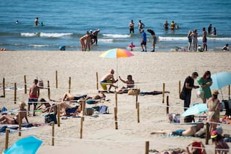 People sunbath at 'Couchant or Sunset beach' in roped off distancing zones marked out by the municipality along the beach in La Grande Motte, southern France, on May 21, 2020, as the nation eases lockdown measures taken to curb the spread of the COVID-19 pandemic, caused by the novel coronavirus. - The local municipality dubbed this set up 'organized beaches', the first in France to implement separated zones for beach goers in order to respect social distancing. (Photo by CLEMENT MAHOUDEAU / AFP)