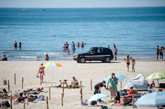 French Gendarmes patrol the beach as people sunbath at 'Couchant or Sunset beach' in roped off distancing zones marked out by the municipality along the beach in La Grande Motte, southern France, on May 21, 2020, as the nation eases lockdown measures taken to curb the spread of the COVID-19 pandemic, caused by the novel coronavirus. - The local municipality dubbed this set up 'organized beaches', the first in France to implement separated zones for beach goers in order to respect social distancing. (Photo by CLEMENT MAHOUDEAU / AFP)