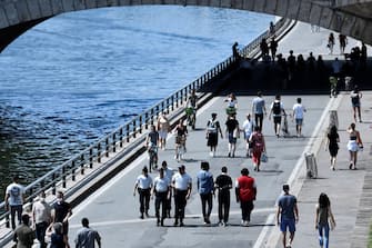 Police officers patrol among people enjoying the sun and walking on the banks of the river Seine, in Paris, on May 21, 2020 as France eases lockdown measures taken to curb the spread of the COVID-19 (the novel coronavirus). (Photo by STEPHANE DE SAKUTIN / AFP)