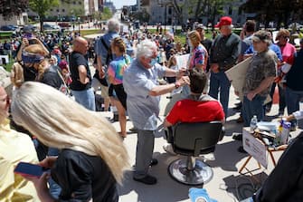 LANSING, MI - MAY 20: Owosso barber, Karl Manke, gives a free haircut to Parker Shonts, of Lake Orion, on the steps of the state Capitol during Operation Haircut on May 20, 2020 in Lansing, Michigan. The event was a protest planned by the Michigan Conservative Coalition in response to an Owosso barber, Karl Manke, whose business license was taken away after he violated the stay-at-home order by reopening. The protest is part of a growing national movement against stay-at-home orders that are designed to help slow the spread of the coronavirus (COVID-19). (Photo by Elaine Cromie/Getty Images)