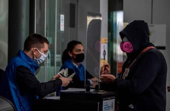 Migration workers check a passenger at El Dorado international airport in Bogota on May 18, 2020. (Photo by Juan BARRETO / AFP) (Photo by JUAN BARRETO/AFP via Getty Images)