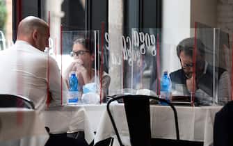 People have lunch at tables partitioned with plexiglas at the Goga Cafe on May 18, 2020 in central Milan during the country's lockdown aimed at curbing the spread of the COVID-19 infection, caused by the novel coronavirus. - Restaurants and churches reopen in Italy on May 18, 2020 as part of a fresh wave of lockdown easing in Europe and the country's latest step in a cautious, gradual return to normality, allowing businesses and churches to reopen after a two-month lockdown. (Photo by Miguel MEDINA / AFP) (Photo by MIGUEL MEDINA/AFP via Getty Images)