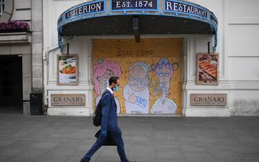 A man wearing a face mask walks past a boarded up restaurant near Piccadilly Circus in London's main high street  shopping area on May 22, 2020 as lockdown restrictions to combat the spread of the novel coronavirus remain in place. - UK retail sales dived by a record 18.1 percent in April with the country in coronavirus lockdown, triggering a surge in government borrowing to an unprecedented level, data showed on May 22. (Photo by DANIEL LEAL-OLIVAS / AFP) (Photo by DANIEL LEAL-OLIVAS/AFP via Getty Images)