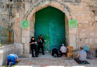 Israeli security forces look on as Palestinian worshippers perform the last Friday prayer of the Muslim holy month of Ramadan, outside the closed al-Aqsa mosque compound in the Old City of Jerusalem, amid the novel coronavirus pandemic crisis, on May 22, 2020. (Photo by AHMAD GHARABLI / AFP) (Photo by AHMAD GHARABLI/AFP via Getty Images)