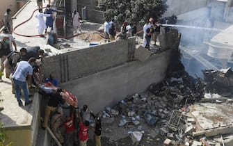 Rescue workers move a body from the site after a Pakistan International Airlines aircraft after crashed at a  residential area in Karachi on May 22, 2020. - A Pakistan passenger plane with more than 100 people believed to be on board crashed in the southern city of Karachi on May 22, the country's aviation authority said. (Photo by Asif HASSAN / AFP) (Photo by ASIF HASSAN/AFP via Getty Images)