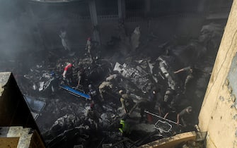 Rescue workers search for victims at the site after a Pakistan International Airlines aircraft crashed at a residential area in Karachi on May 22, 2020. - A Pakistani passenger plane with nearly 100 people on board crashed into a residential area of the southern city of Karachi on May 22. (Photo by Asif HASSAN / AFP) (Photo by ASIF HASSAN/AFP via Getty Images)