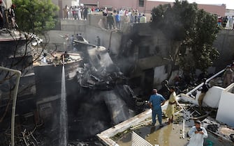Firefighters spray water on the wreckage of a Pakistan International Airlines aircraft after it crashed at a residential area in Karachi on May 22, 2020. - A Pakistani passenger plane with nearly 100 people on board crashed into a residential area of the southern city of Karachi on May 22. (Photo by Rizwan TABASSUM / AFP) (Photo by RIZWAN TABASSUM/AFP via Getty Images)