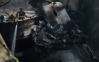 A firefighter sprays water on the wreckage of a Pakistan International Airlines aircraft after it crashed in a residential area in Karachi on May 22, 2020. - A Pakistani plane with nearly 100 people on board crashed into a residential area in the southern city of Karachi on May 22, killing several people on the ground. (Photo by Rizwan TABASSUM / AFP) (Photo by RIZWAN TABASSUM/AFP via Getty Images)