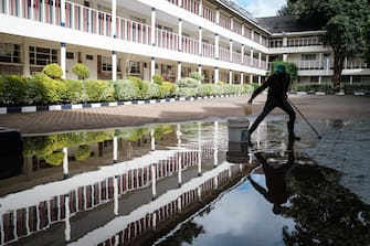 A staff clears a puddle of rain at Saint Hannah's School closed due to the novel coronavirus COVID-19, in Nairobi, on April 29, 2020. (Photo by Yasuyoshi CHIBA / AFP) (Photo by YASUYOSHI CHIBA/AFP via Getty Images)