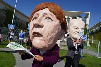 BERLIN, GERMANY - MAY 27: Activists dressed as German Chancellor Angela Merkel and Finance Minister Olaf Scholz take part in a protest outside the Chancellery against the recent Lufthansa bailout on May 27, 2020 in Berlin, Germany. The German government announced Monday it will prop up German airline Lufthansa with a EUR 9 billion package that includes a 20% government stake in the company. The activists were protesting both against the fiscal and the environmental implications of the bailout.  (Photo by Sean Gallup/Getty Images)