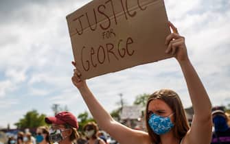 A woman holds up a sign during a protest near where a Minneapolis Police Department officer allegedly killed George Floyd, on May 26, 2020 in Minneapolis, Minnesota. - A video of a handcuffed black man dying while a Minneapolis officer knelt on his neck for more than five minutes sparked a fresh furor in the US over police treatment of African Americans Tuesday. Minneapolis Mayor Jacob Frey fired four police officers following the death in custody of George Floyd on Monday as the suspect was pressed shirtless onto a Minneapolis street, one officer's knee on his neck. (Photo by Kerem Yucel / AFP) (Photo by KEREM YUCEL/AFP via Getty Images)