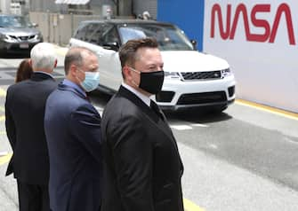 CAPE CANAVERAL, FLORIDA - MAY 27: SpaceX founder Elon Musk (L) wears a face mask as he watches NASA astronauts Bob Behnken and Doug Hurley depart from the Operations and Checkout Building on their way to the SpaceX Falcon 9 rocket with the Crew Dragon spacecraft on launch pad 39A at the Kennedy Space Center on May 27, 2020 in Cape Canaveral, Florida. The inaugural flight will be the first manned mission since the end of the Space Shuttle program in 2011 to be launched into space from the United States.  (Photo by Joe Raedle/Getty Images)