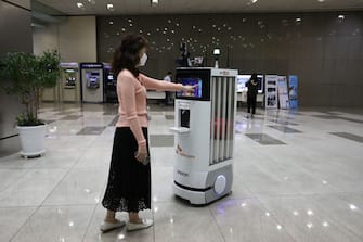 SEOUL, SOUTH KOREA - MAY 26: An employee of SK Telecom demonstrates a robot that will be used for disinfection, checking body temperature at their company headquarters on May 26, 2020 in Seoul, South Korea. SK Telecom has developed a new autonomous robot to handle disinfection and monitoring duties as part of efforts to prevent the spread of coronavirus (COVID-19), the company said. It will also monitor the temperatures of people around it and check whether they are wearing face masks. Those who are not wearing masks will be asked to do so by the robot if there are too many people around. They said it hopes the robots will lessen the workloads of people who are performing monitoring duties amid the COVID-19 pandemic. (Photo by Chung Sung-Jun/Getty Images)