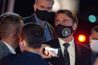 BRASILIA, BRAZIL - MAY 27: President of Brazil Jair Bolsonaro, wearing a face mask with a print of Brazil's Coat of Arms and written God above all, Brazil above all, reacts to supporters of his government who waited for him outside the Palácio do Alvorada amidst the coronavirus (COVID-19) pandemic on May 27, 2020 in Brasilia. Brazil has over 411,000 confirmed positive cases of Coronavirus and 25,598 deaths. (Photo by Andressa Anholete/Getty Images)