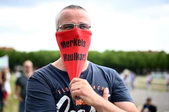 MUNICH, GERMANY - MAY 23: A Protester wears a face mask with the words "Merkels Maulkorb" (Merkels muzzle) prior to a  demonstration against lockdown measures and government policy during the coronavirus crisis on May 23, 2020 in Munich, Germany. The protests, which include people from the far political left to the far right, from conspiracy theorists to anti-vaccinators, but also the simply disgruntled, have become a weekly event in cities across Germany despite the fact that authorities have eased most lockdown measures. (Photo by Sebastian Widmann/Getty Images)
