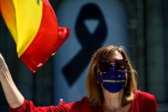 A demonstrator wearing a mask calling for the resignation of the government waves a Spanish flag while driving past the Puerta de Alcala during a "caravan for Spain and its freedom" protest by far-right party Vox against the Spanish government in Madrid on May 23, 2020. - Spain, one of the most affected countries in the world by the novel coronavirus with 28,628 fatalities, has extended until June 6 the state of emergency which significantly limits the freedom of movement to fight the epidemic. The left-wing government's management of the crisis has drawn a barrage of criticism from righ-wing parties who have denounced its "brutal confinement". (Photo by JAVIER SORIANO / AFP) (Photo by JAVIER SORIANO/AFP via Getty Images)